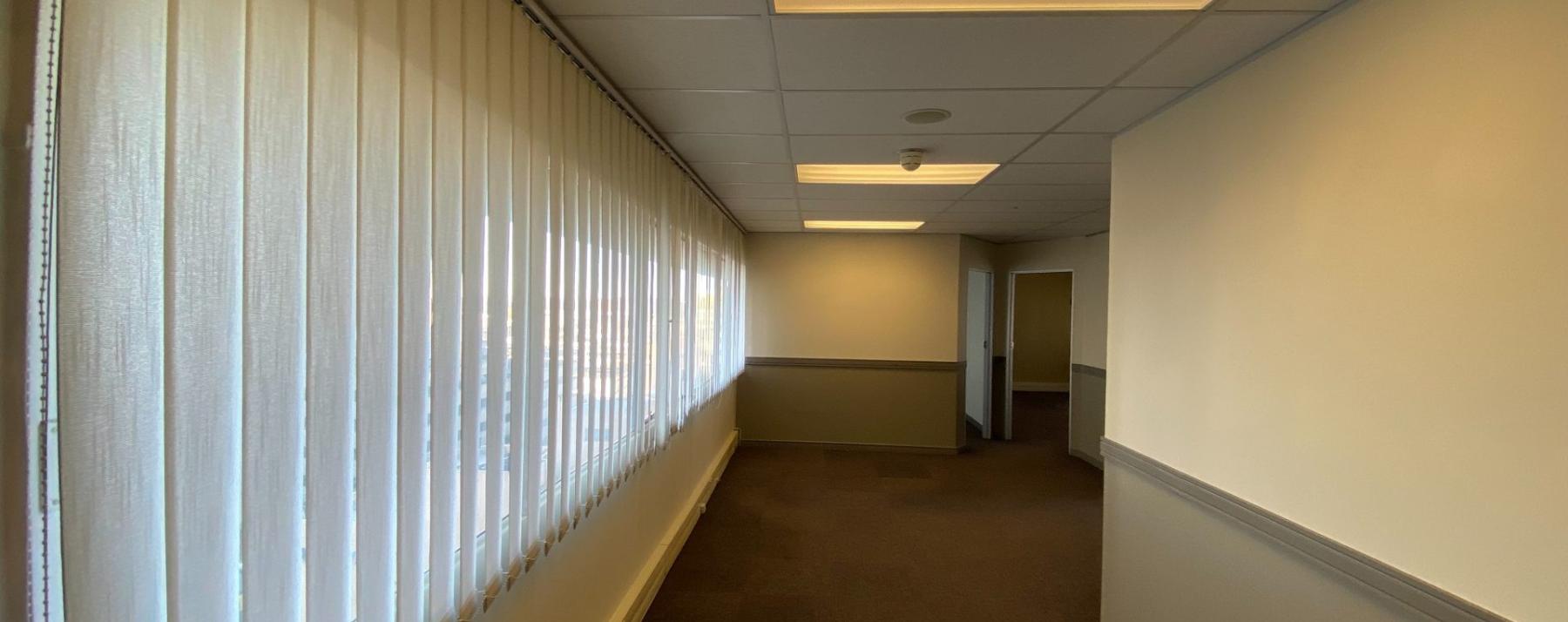 Commercial office corridor with vertical blinds and carpet flooring