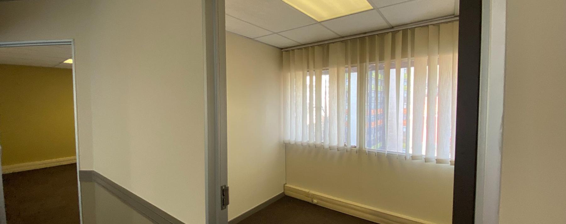 Small private office with corner windows and neutral interior finishes