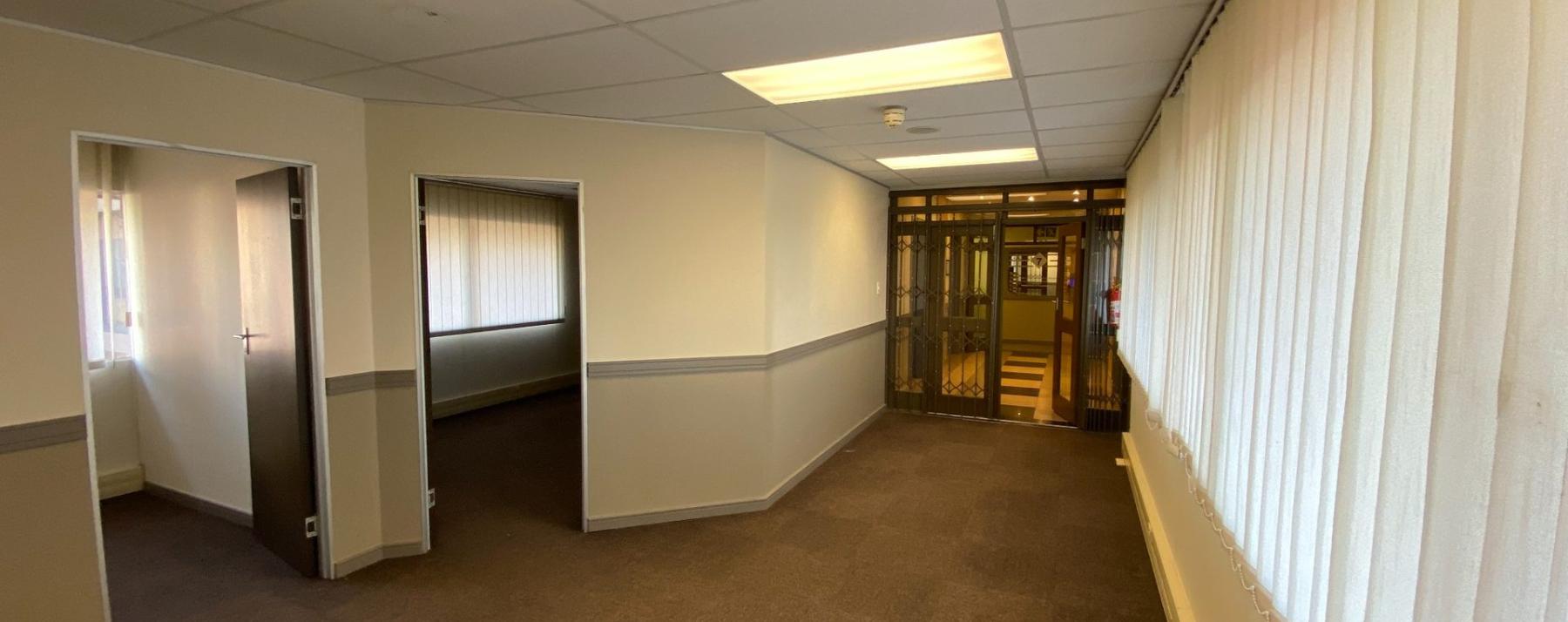 Open commercial office space with multiple private office entrances and natural light