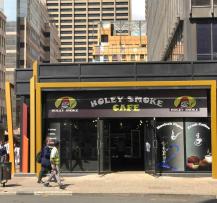 Street view of Holey Smoke Café storefront with pedestrians walking through the city business district.